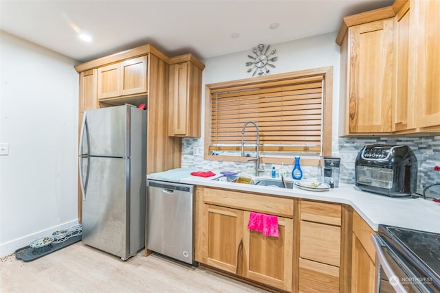 kitchen with appliances with stainless steel finishes, light hardwood / wood-style floors, tasteful backsplash, and sink