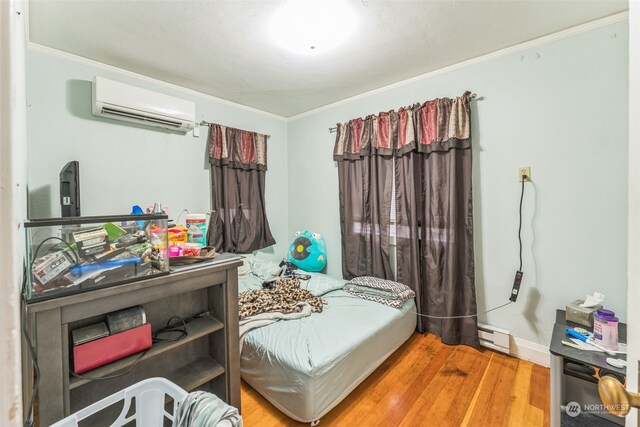 bedroom featuring hardwood / wood-style flooring, ornamental molding, baseboard heating, and a wall mounted AC