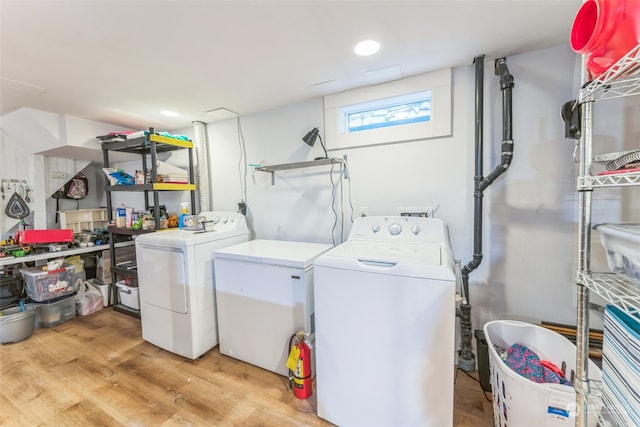 laundry room with separate washer and dryer and light hardwood / wood-style flooring