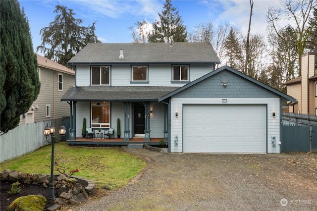 view of property with covered porch, a garage, and a front yard