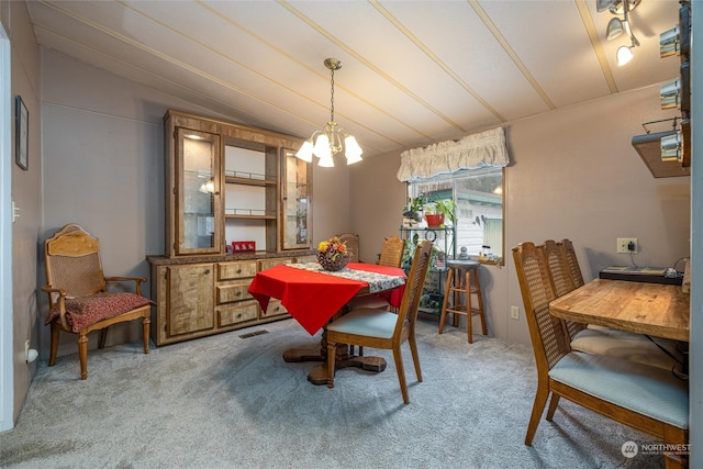 dining room with carpet, lofted ceiling, and an inviting chandelier