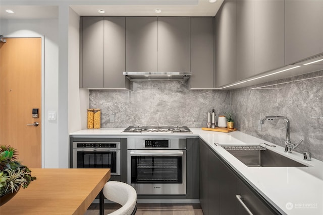 kitchen featuring gray cabinets, decorative backsplash, sink, and appliances with stainless steel finishes