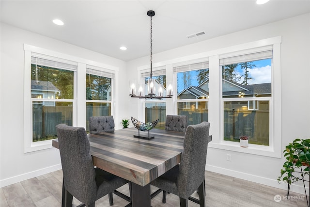 dining space featuring plenty of natural light, wood-type flooring, and an inviting chandelier