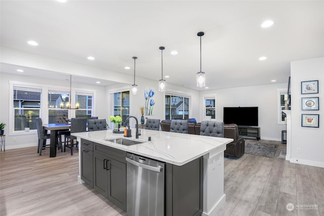 kitchen with dishwasher, sink, an island with sink, decorative light fixtures, and light hardwood / wood-style floors