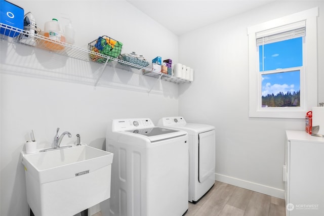 laundry room with washing machine and dryer, light wood-type flooring, and sink