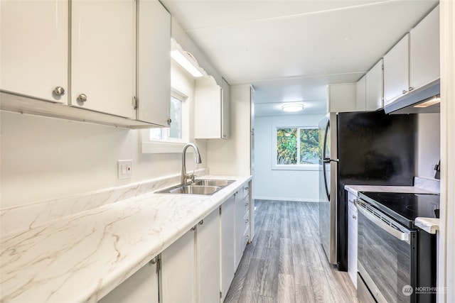 kitchen with white cabinets, appliances with stainless steel finishes, light hardwood / wood-style floors, and sink