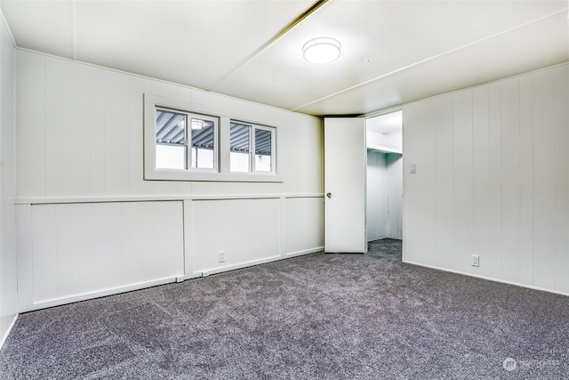 carpeted spare room featuring wooden walls