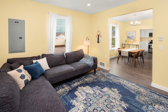 living room with electric panel, a chandelier, and hardwood / wood-style flooring