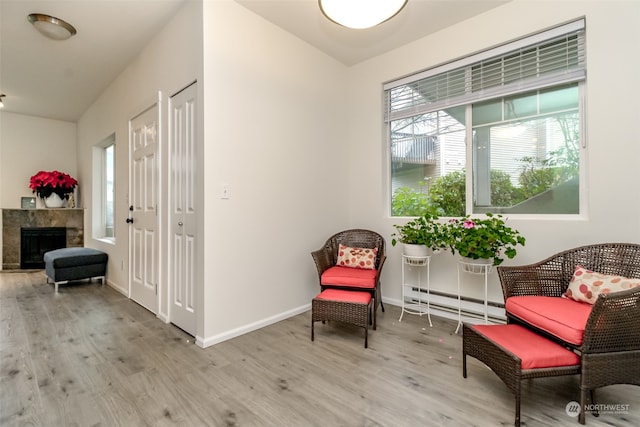 living area with light wood-type flooring, a fireplace, and a baseboard radiator