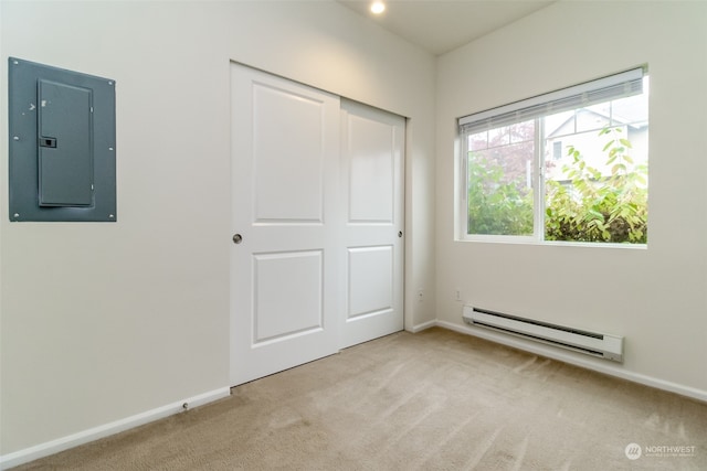 unfurnished bedroom featuring electric panel, light carpet, a closet, and a baseboard heating unit