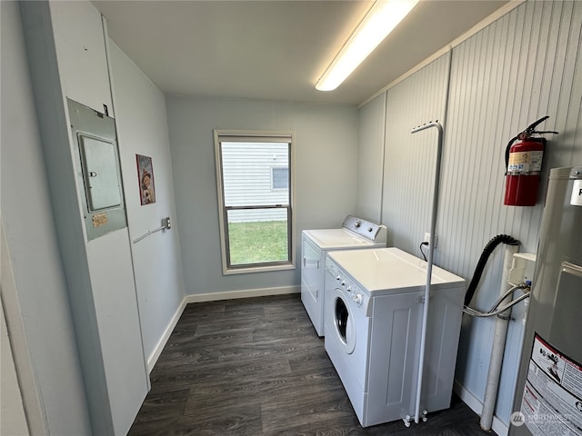 clothes washing area featuring washing machine and clothes dryer, water heater, and dark hardwood / wood-style floors