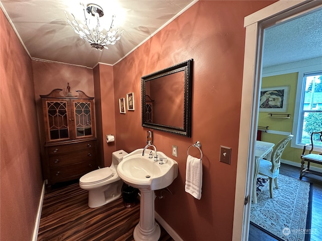 bathroom featuring a chandelier, wood-type flooring, toilet, and ornamental molding