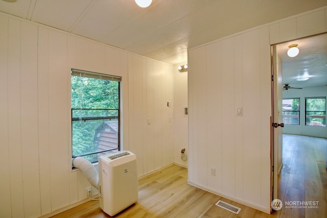 unfurnished room featuring ceiling fan, wood walls, and light hardwood / wood-style flooring