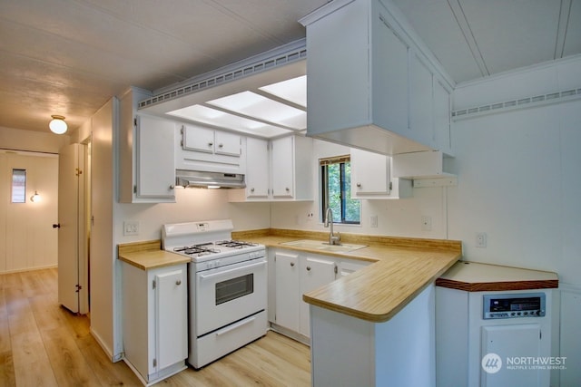 kitchen with ventilation hood, white range oven, white cabinetry, and sink