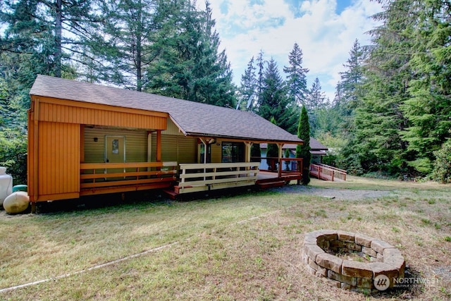 view of front facade with a wooden deck, a fire pit, and a front yard