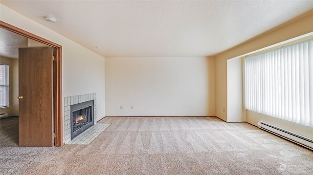 unfurnished living room with a textured ceiling, light colored carpet, a healthy amount of sunlight, and a baseboard radiator