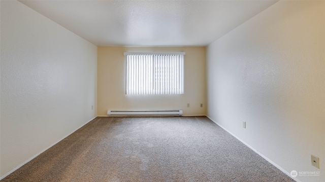 spare room with carpet and a baseboard heating unit