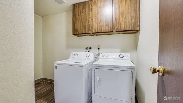 washroom with washing machine and dryer, dark hardwood / wood-style flooring, and cabinets