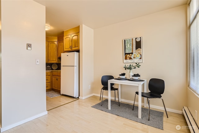 kitchen with white fridge, plenty of natural light, a baseboard heating unit, and light hardwood / wood-style floors