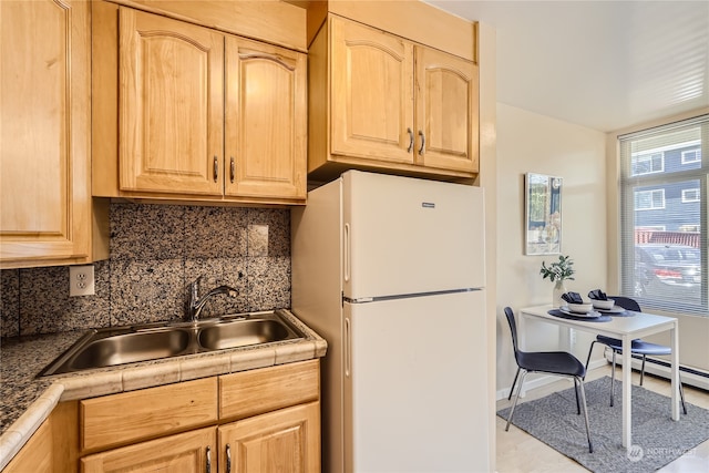 kitchen with light brown cabinets, white fridge, and sink