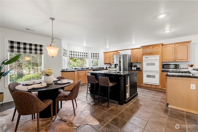 kitchen featuring stainless steel appliances, sink, a center island, hanging light fixtures, and a breakfast bar area