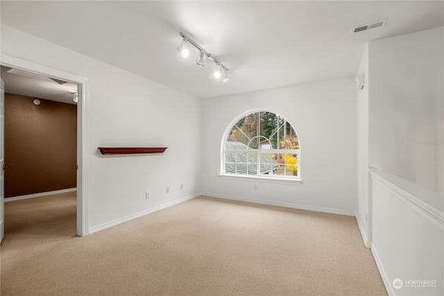 unfurnished room featuring light colored carpet and track lighting