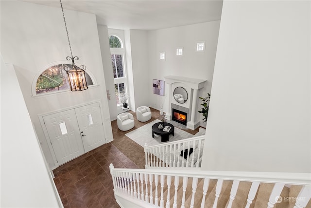 foyer entrance with a fireplace, a high ceiling, and a notable chandelier