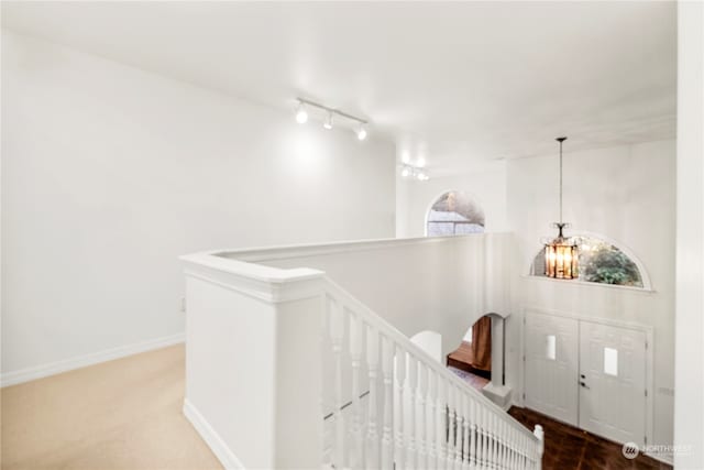 hall featuring a chandelier, carpet floors, and rail lighting