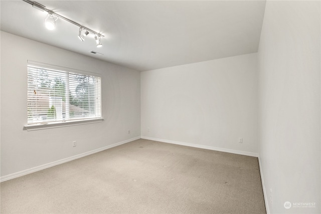 carpeted spare room featuring track lighting