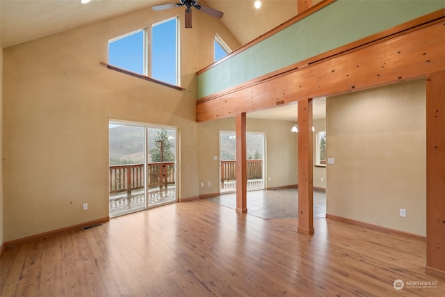 unfurnished living room featuring ceiling fan, light wood-type flooring, and high vaulted ceiling