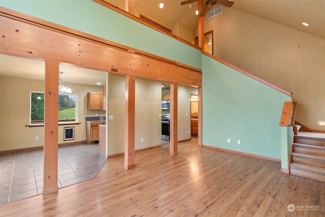 living room with ceiling fan, high vaulted ceiling, and light wood-type flooring