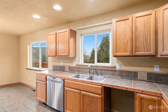 kitchen featuring stainless steel dishwasher, sink, and a wealth of natural light