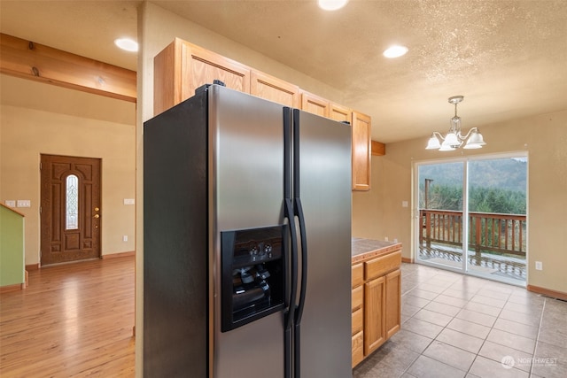 kitchen with stainless steel fridge, light hardwood / wood-style flooring, hanging light fixtures, and light brown cabinetry