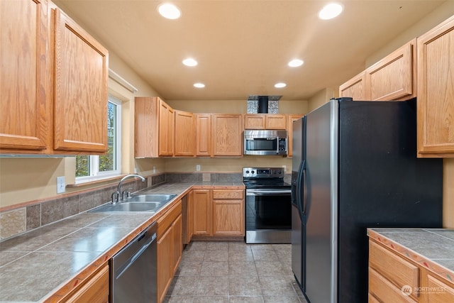 kitchen with light brown cabinets, sink, and black appliances