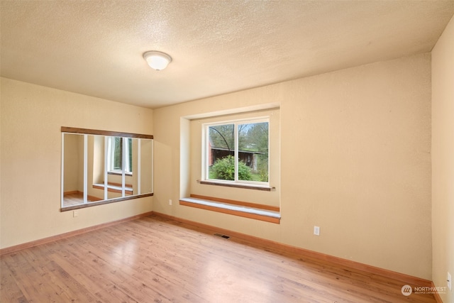 empty room featuring a textured ceiling and light wood-type flooring