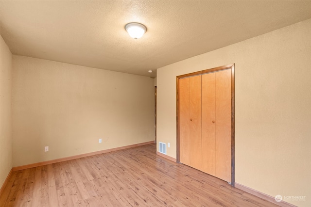 unfurnished bedroom with a closet, light hardwood / wood-style flooring, and a textured ceiling