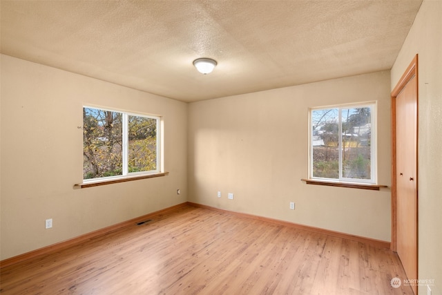 unfurnished room featuring a textured ceiling and light wood-type flooring