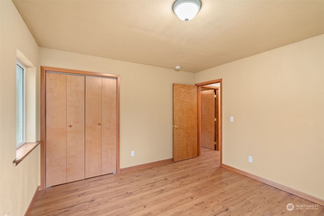 unfurnished bedroom with a textured ceiling, light hardwood / wood-style flooring, and a closet