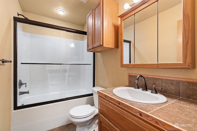 full bathroom featuring combined bath / shower with glass door, a textured ceiling, vanity, and toilet