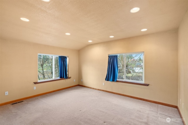 unfurnished room featuring carpet, plenty of natural light, and vaulted ceiling