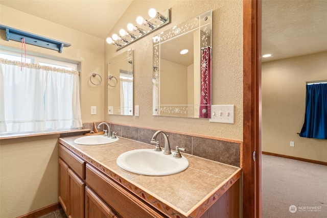 bathroom featuring vanity, a healthy amount of sunlight, and vaulted ceiling