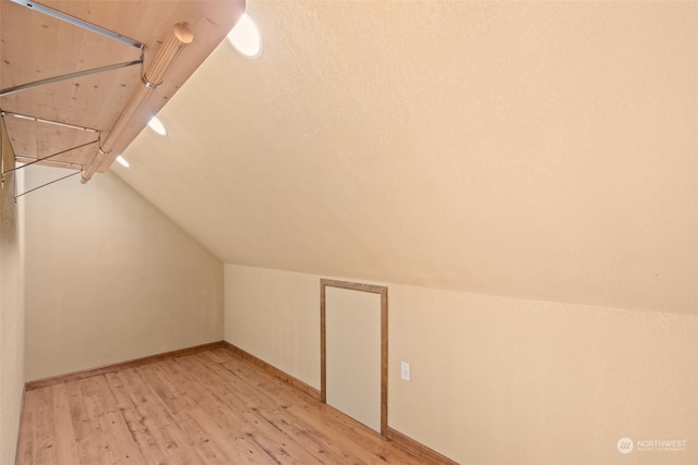 additional living space with light hardwood / wood-style floors and vaulted ceiling