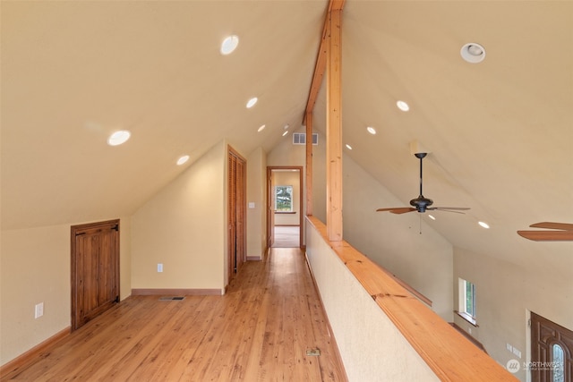 hallway featuring plenty of natural light, vaulted ceiling, and light wood-type flooring