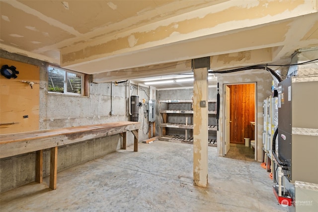 basement with electric panel, heating unit, strapped water heater, and a workshop area