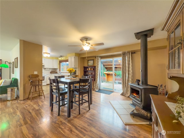 dining room featuring ceiling fan, a wood stove, and light hardwood / wood-style flooring