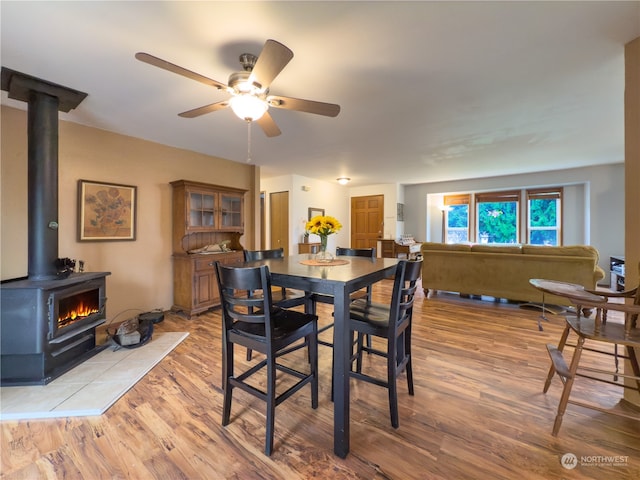 dining room featuring ceiling fan, light hardwood / wood-style floors, and a wood stove