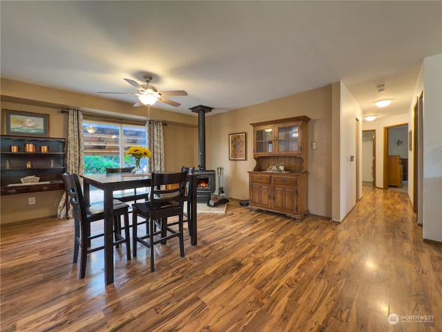 dining space featuring ceiling fan, dark hardwood / wood-style floors, and a wood stove