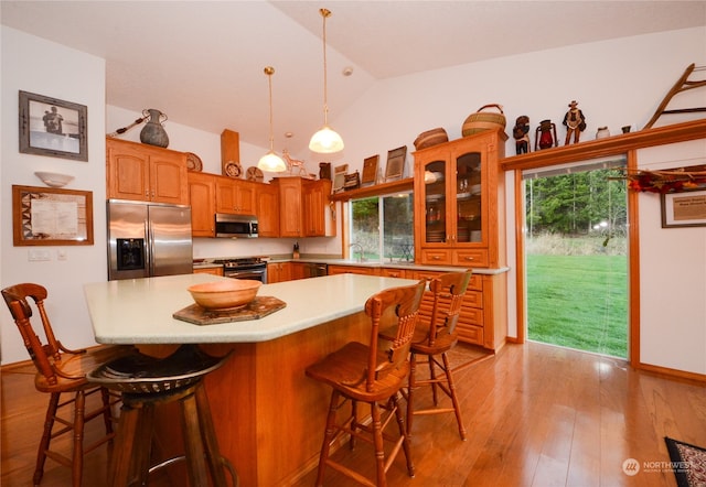 kitchen with a center island, lofted ceiling, a breakfast bar area, appliances with stainless steel finishes, and light wood-type flooring