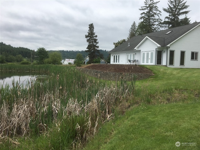 view of yard featuring a water view and french doors