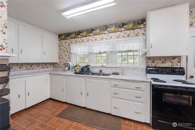 2245 Salzer Valley Rd, Centralia, WA 98531 - kitchen featuring range with electric cooktop, wallpapered walls, a sink, light countertops, and white cabinetry